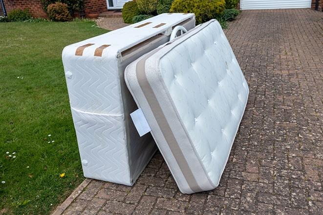 workers lifting mattress out of a cluttered room