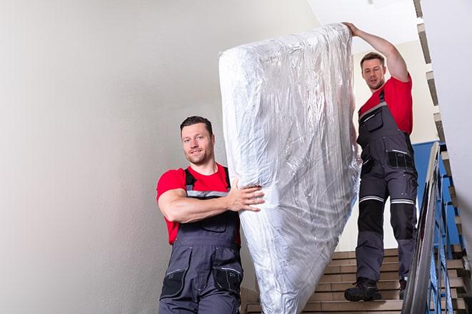 team of workers lifting a box spring out of a house in Maywood